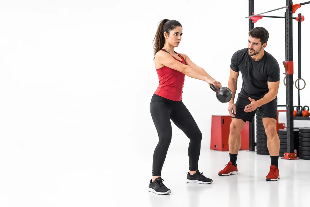Coach enseñando el swing con kettlebell a una principiante